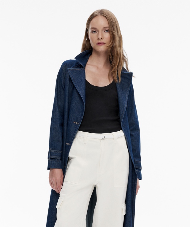 Woman in a denim trench coat, black tank top and white cargo pants and white leather belt