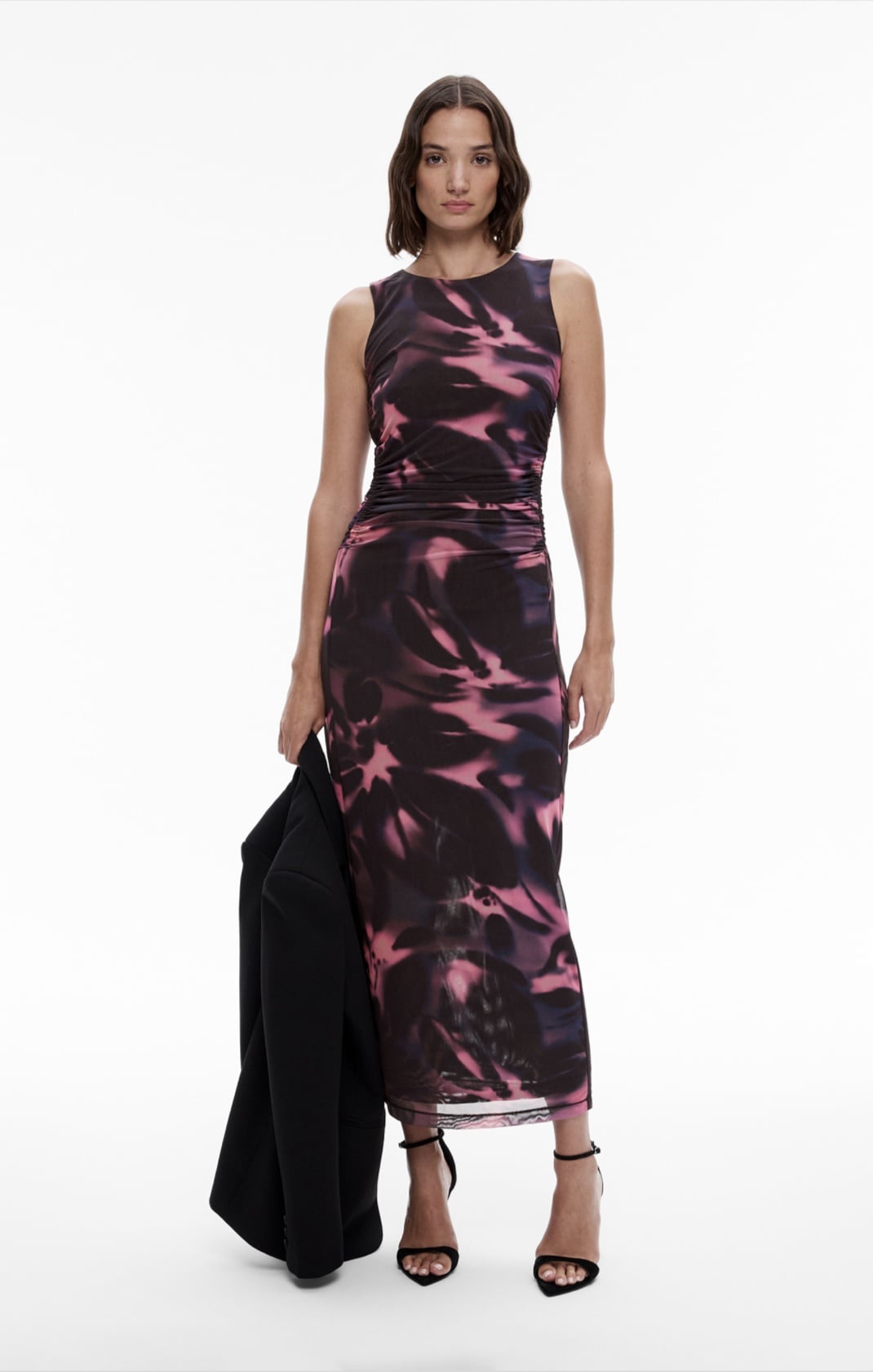 Woman in print midi dress, black blazer and black leather heels