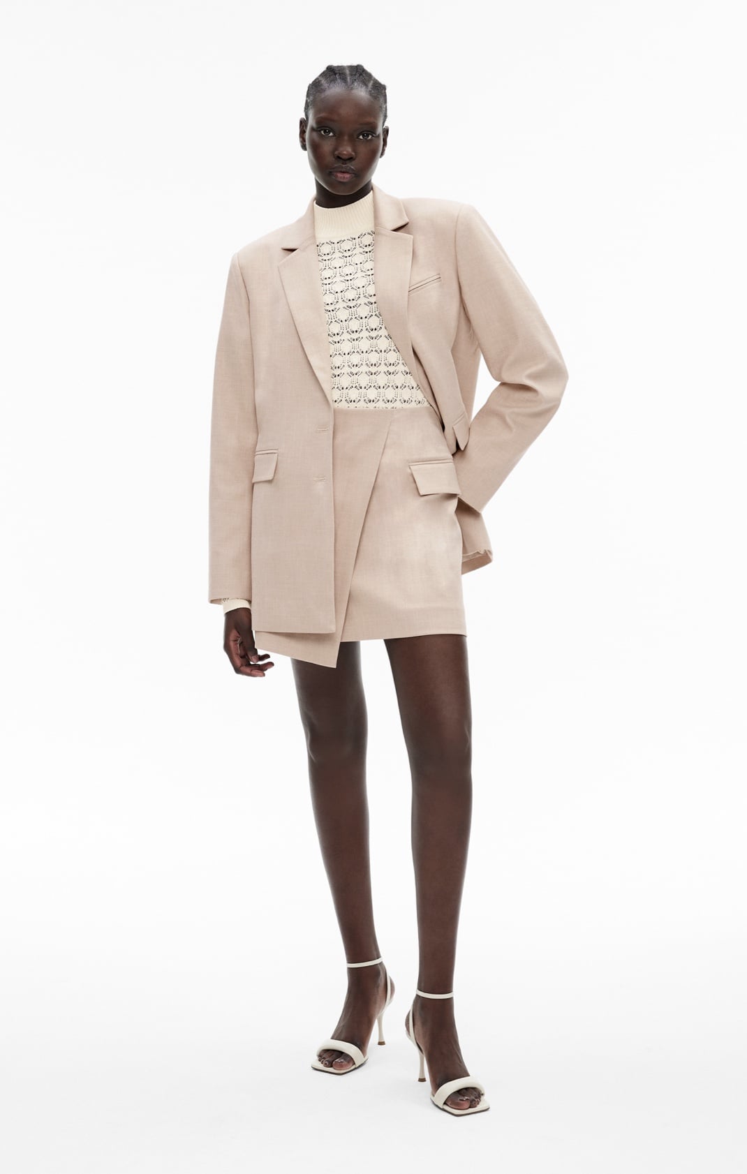 Woman in flax blazer, cream knit top and flax mini skirts