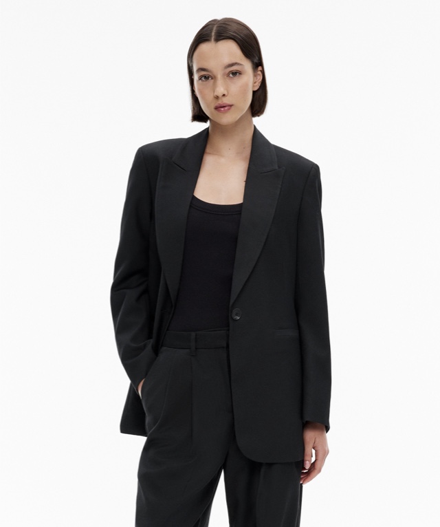 Woman in a black blazer, black tank top and black pants
