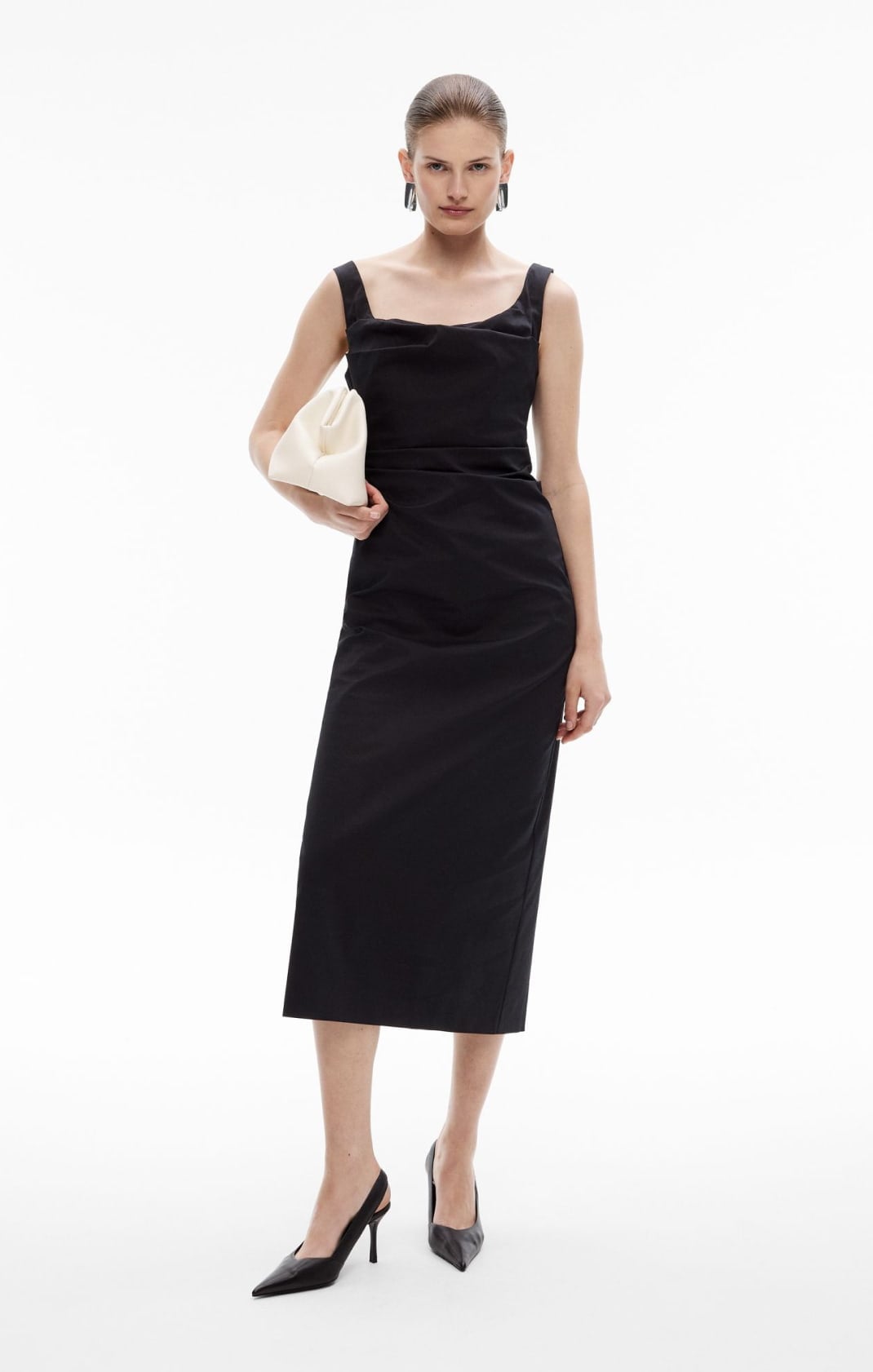 Woman wearing the black ruched midi dress and black point heels