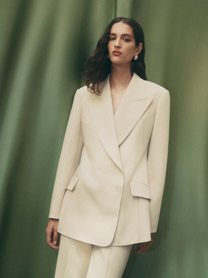 Woman wearing the stone dart blazer, stone exposed dart pant and gold mila pearl stud earrings