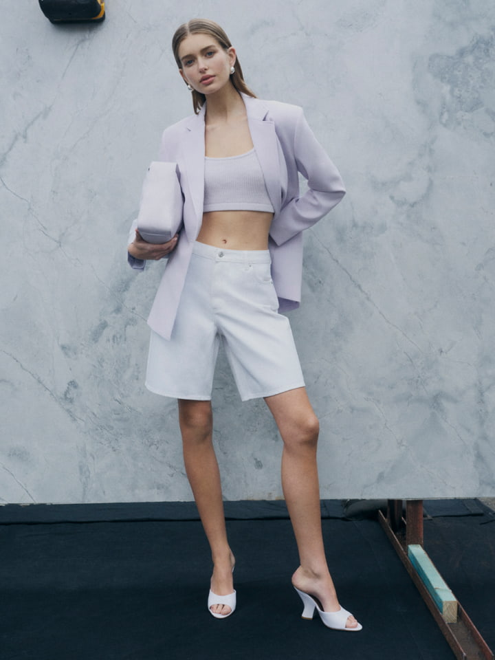 Woman in lilac single breasted slimline blazer, lilac crop rib knit top, white denim bermuda shorts and lilac thalia block mule