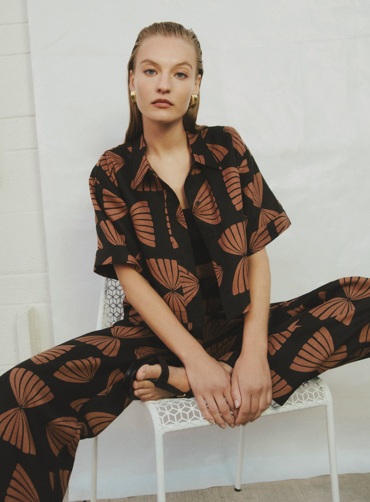 Woman in nutmeg print linen crop shirt, nutmeg print pull on pant, black cropped rib knit top, black billie sandal and black jodie leather bag