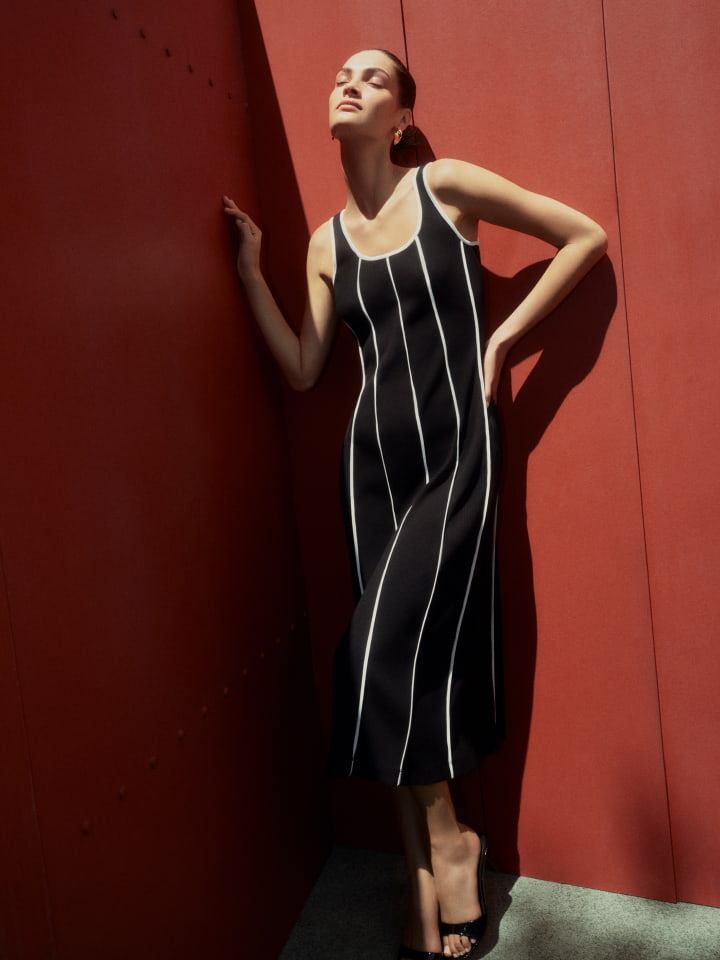Woman in black halter neck knit, white white high rise wid leg jean, black michelle flats and black liv mini leather bag